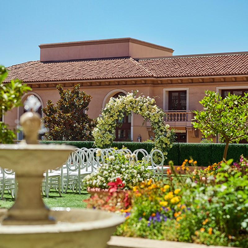 The Garden Terrace - garden set up for a wedding with chairs, an aisle in the middle and flower arch
