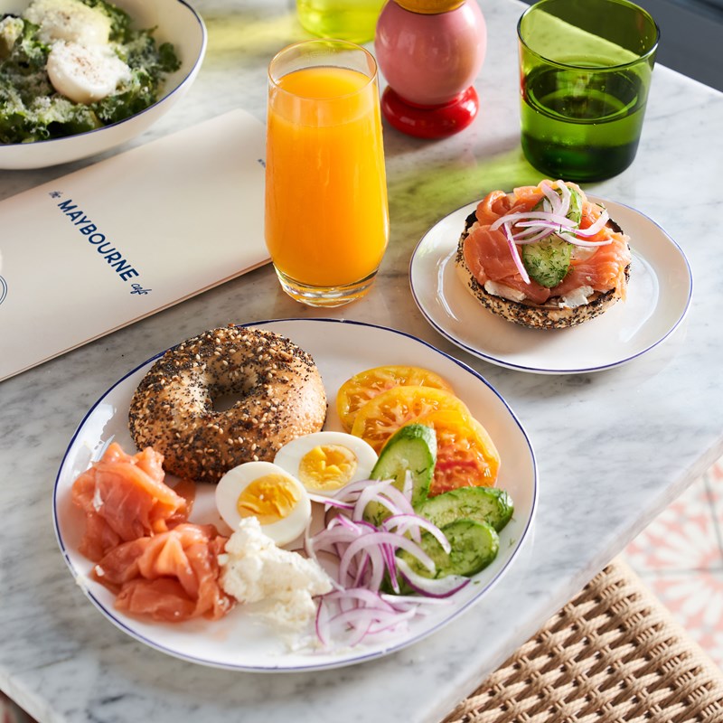 Table with dishes of food including a bagel platter and glass of orange juice