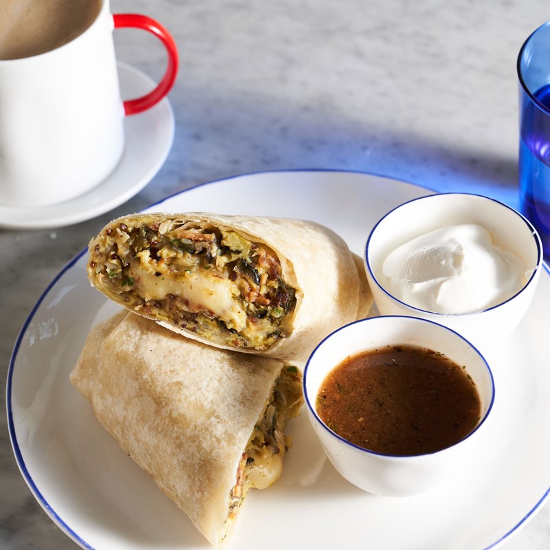 Breakfast burrito on a plate with a cup of coffee and a cup of coffee