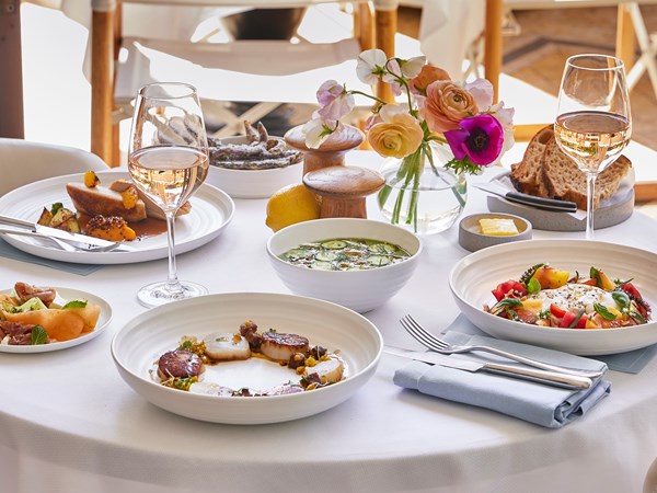 Table with a white tablecloth and dishes food and wine