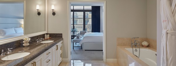 En-suite bathroom with marble cabinets, large bath and dressing gown hung up