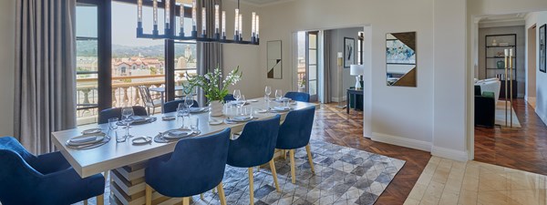 Blue dining chairs around dining table with modern chandelier and terrace doors open in The Residence