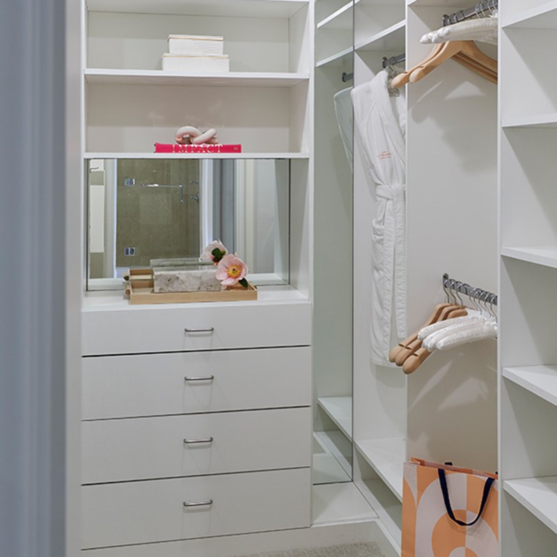 Walk in closet with white interior and hanging dressing gowns in The Residence