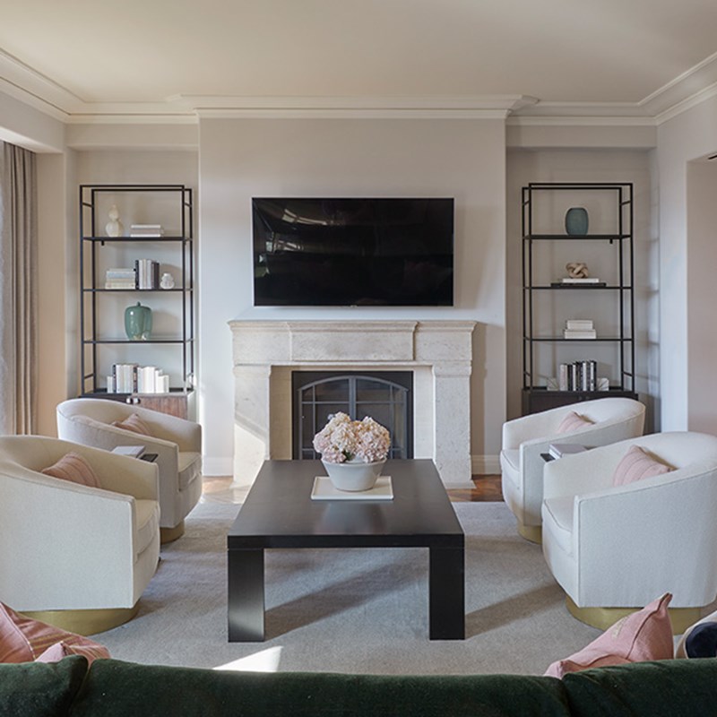 Pale pink sofas around white marble coffee table looking to wall TV in The Residence