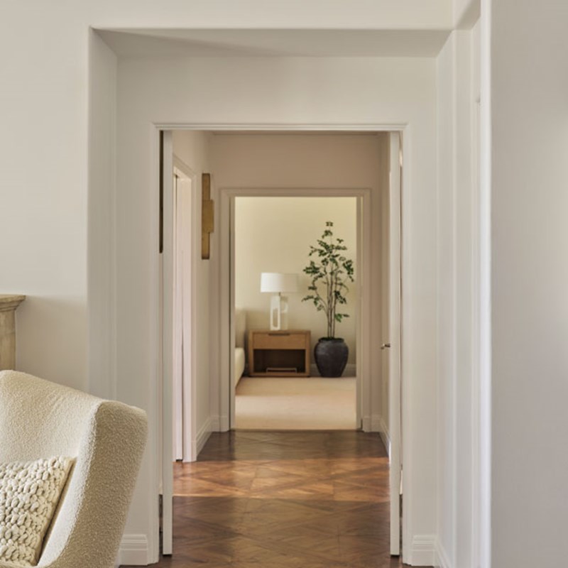 Perspective of looking down the corridor of the Three-bedroom Residence with white walls and a feature table