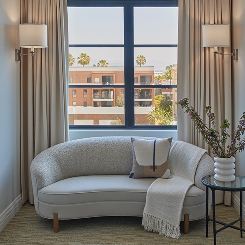 Grey armchair with pillow and throw on it in front of a window